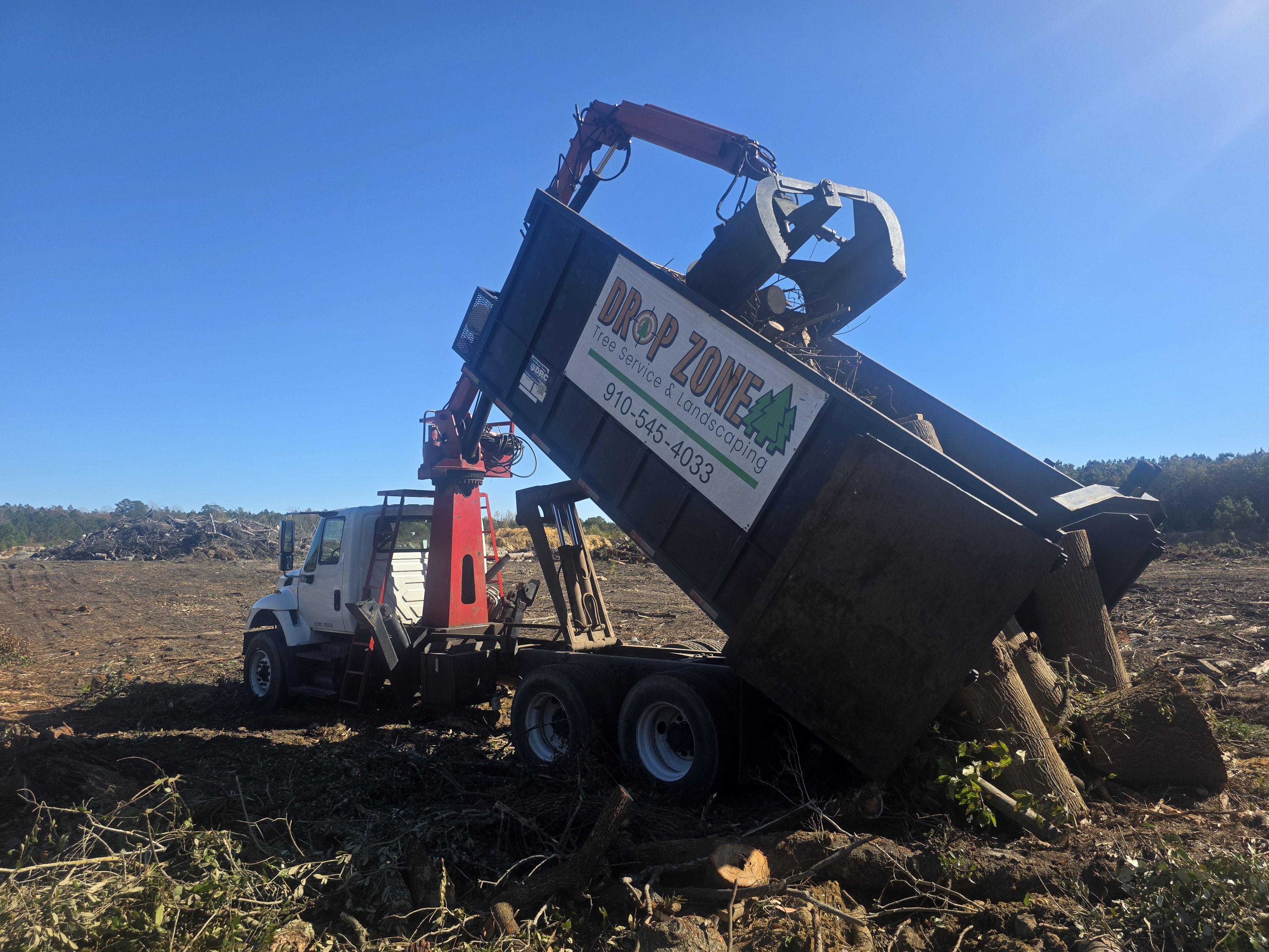 Grapple Truck Removing Vegetation Waste from Dump Bed